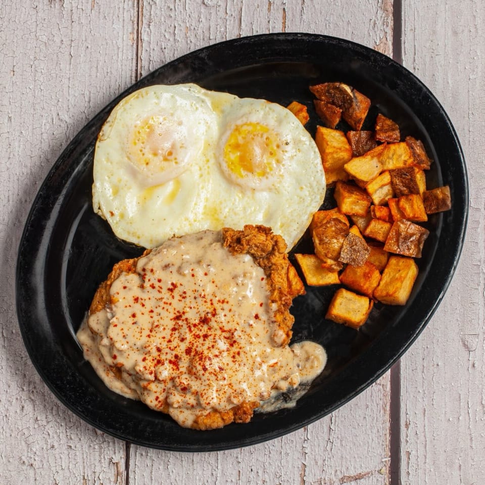 True Grit American Bistro's breakfast: chicken fried steak with gravy, two fried eggs, and home fries.