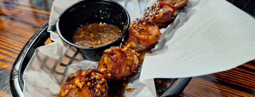 Bacon-wrapped sausage bites with black garlic honey glaze at True Grit American Bistro.