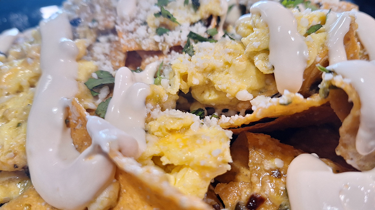 CHILAQUILES VERDE Tortilla chips simmered in tomatillo salsa with scrambled eggs & cheddar topped with cotija cheese and Mexican crema.